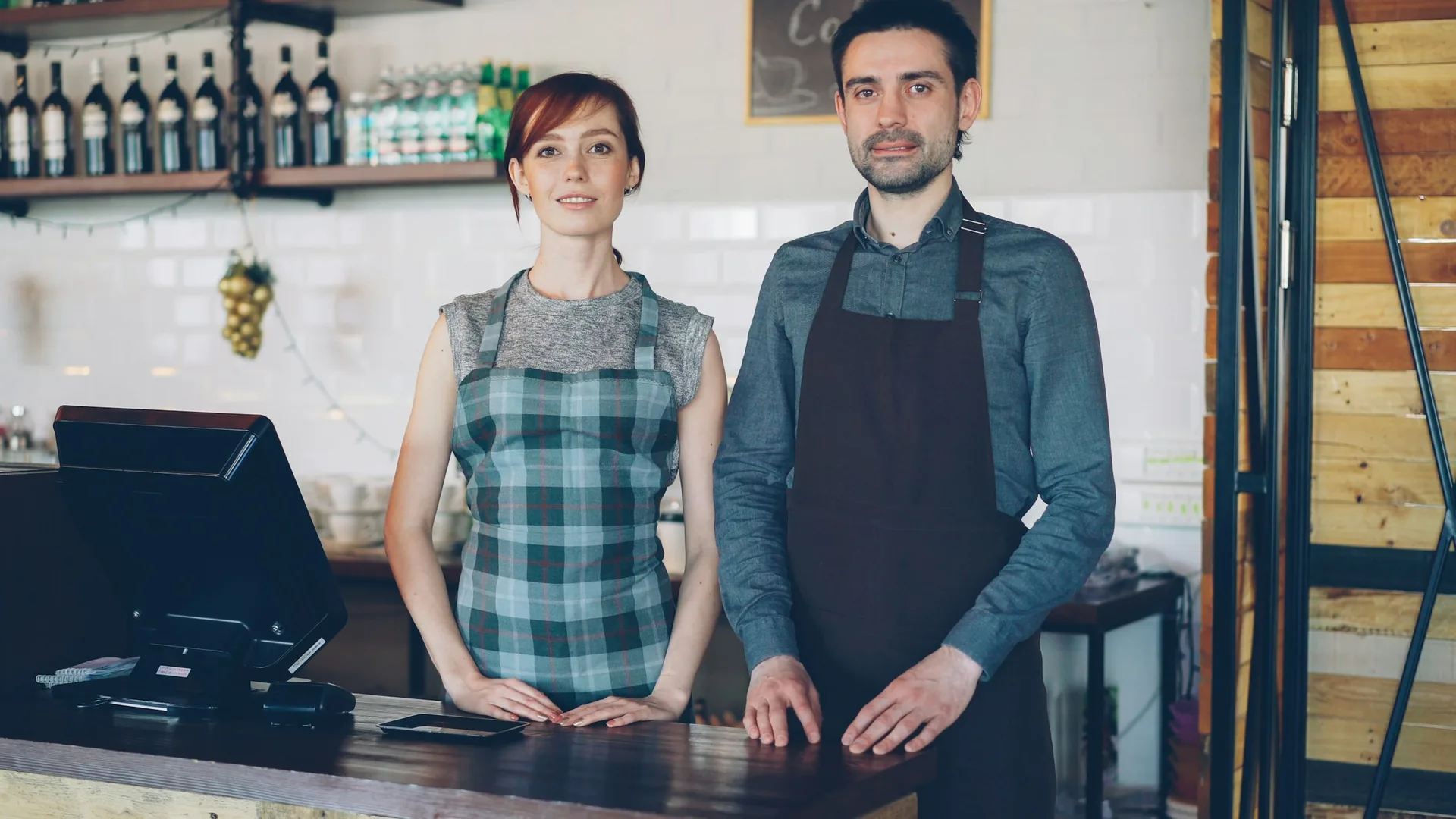 Two small business owners standing behind the counter of their cafe